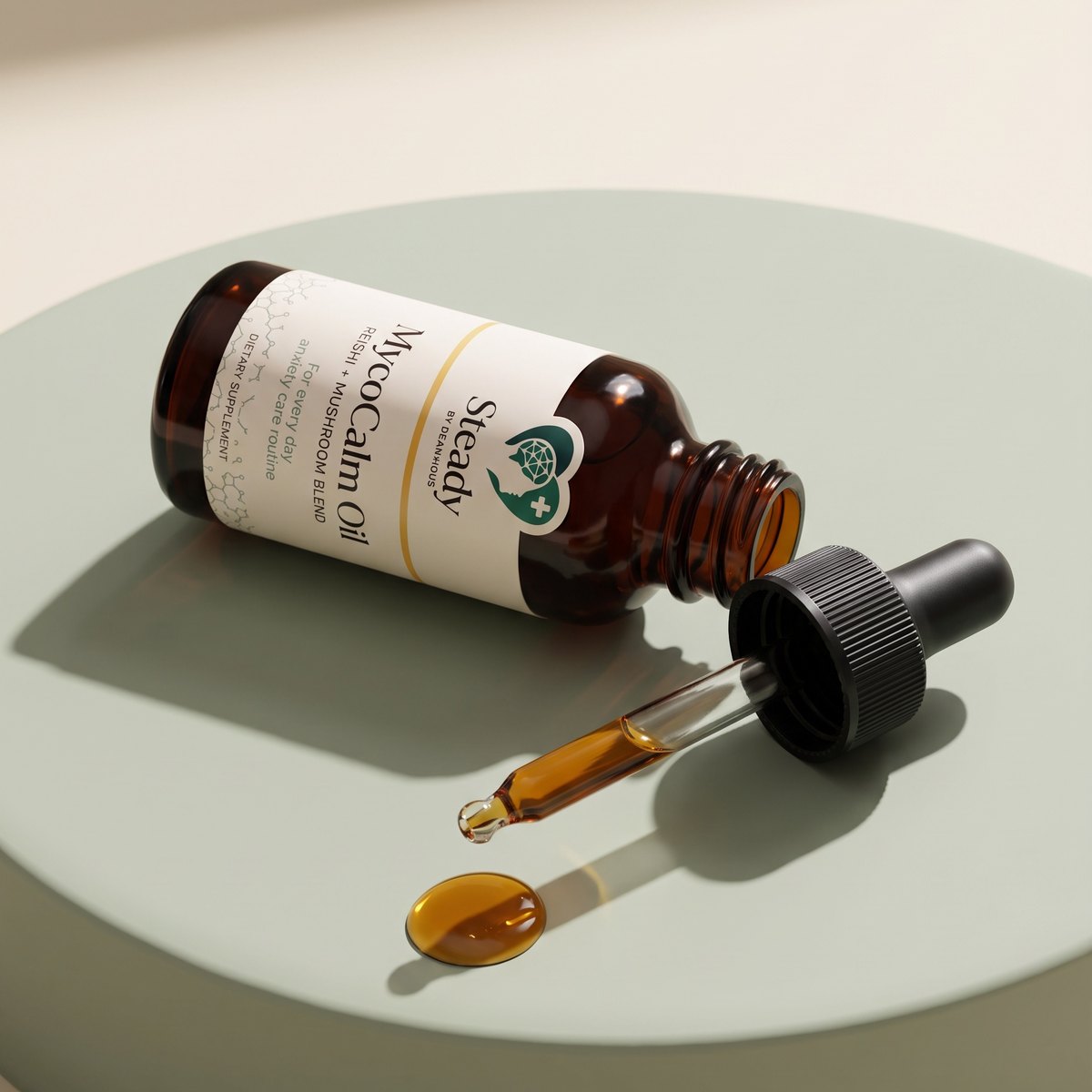 MycoCalm Oil lying on a sage plinth with its dropper beside it and a single amber drop of oil.