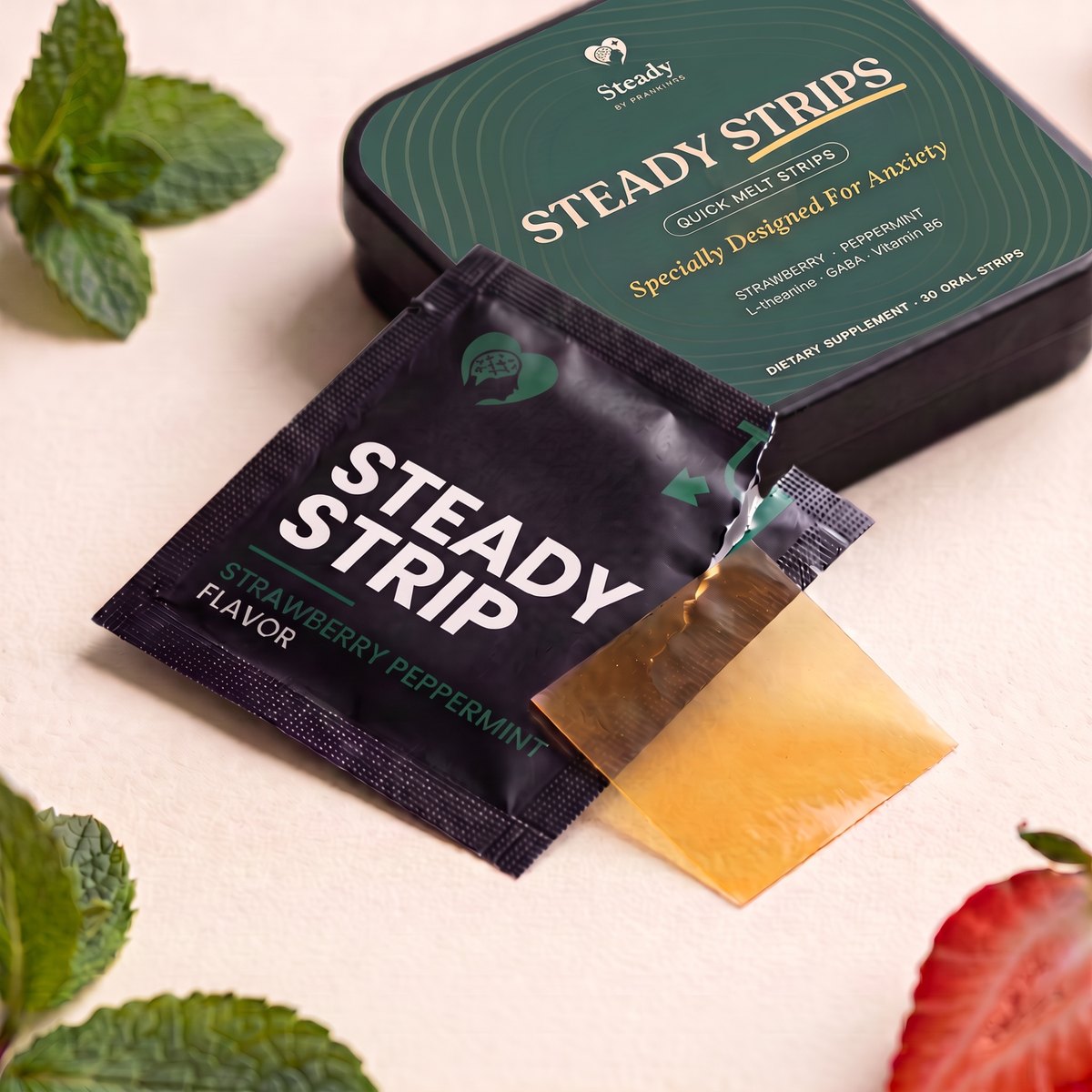 An opened Steady Strip sachet with the amber strip beside it, mint leaves and a strawberry around the green tin.